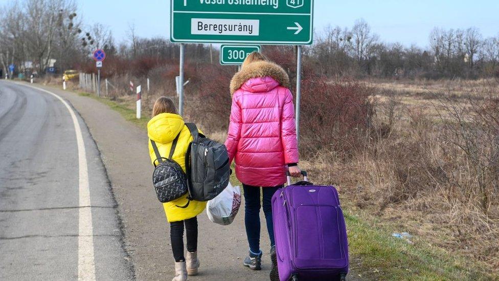 A Ukrainian mother walks with her daughter along the road from the Hungarian-Ukrainian border crossing near Beregsurany, Hungary,