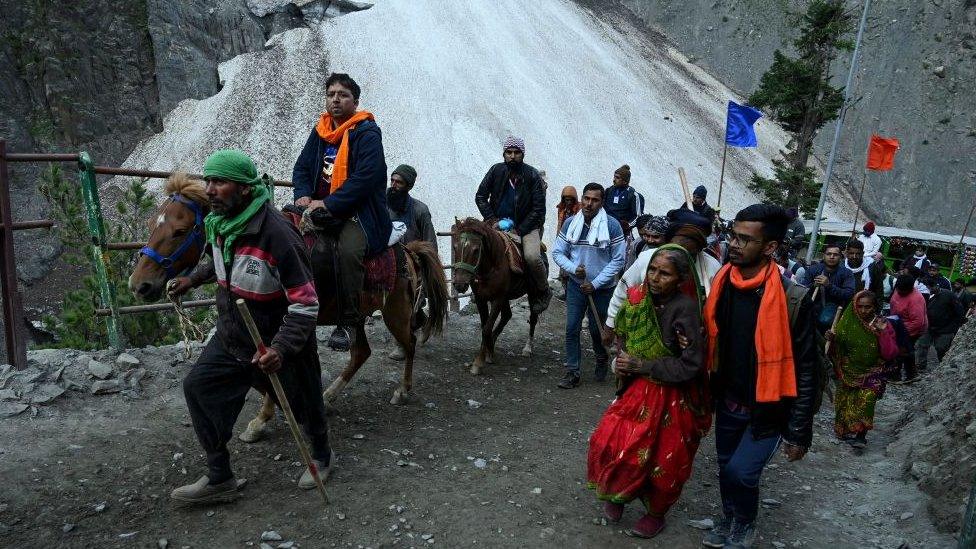 Hindu devotees make their way on foot and on mules along a mountain path during their pilgrimage to the cave shrine of Amarnath, near Baltal on June 30, 2022.