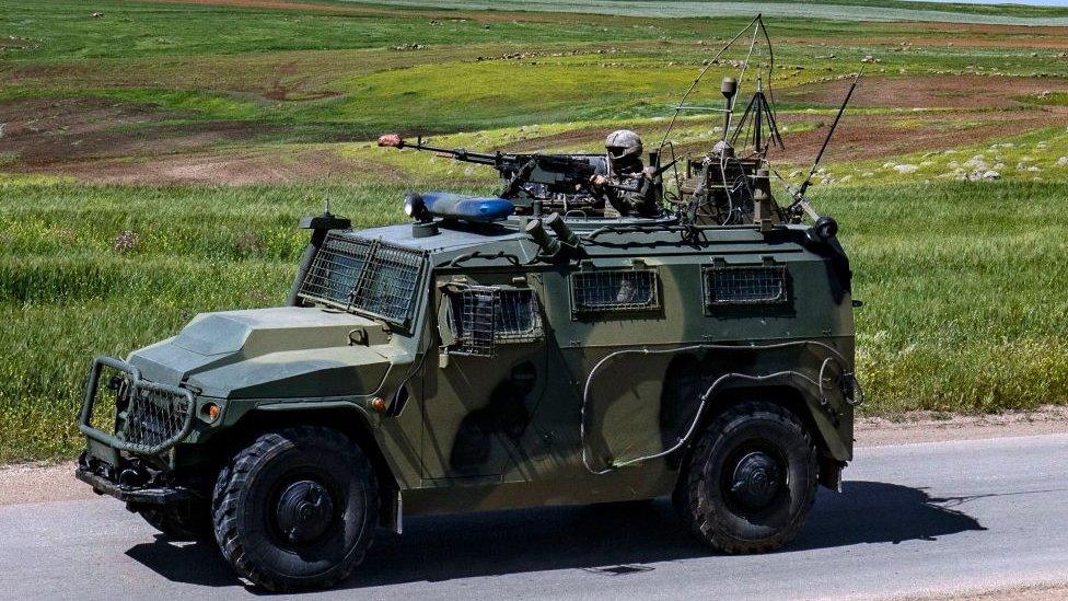 A soldier mans a machine gun mounted on an army vehicle during a Turkish and Russian military patrol in Syria