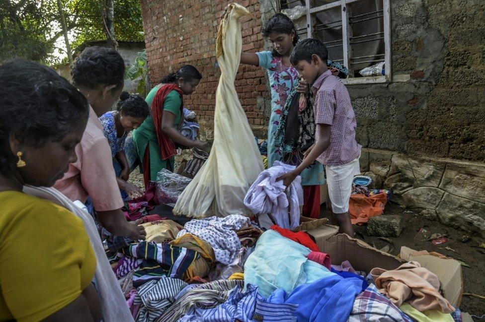 Locals go through clothes donated by relief workers in Mumndancava village, Kerala