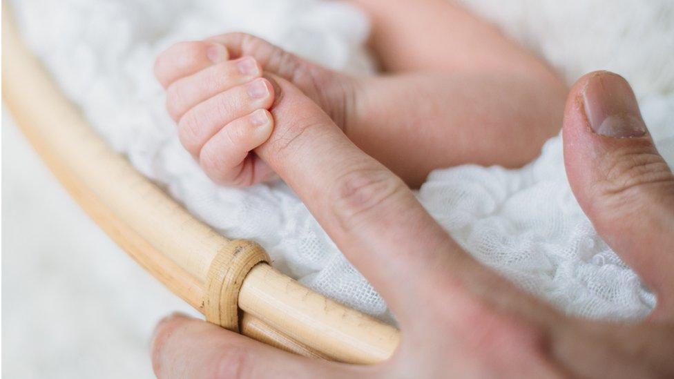 Baby clasps mum's finger