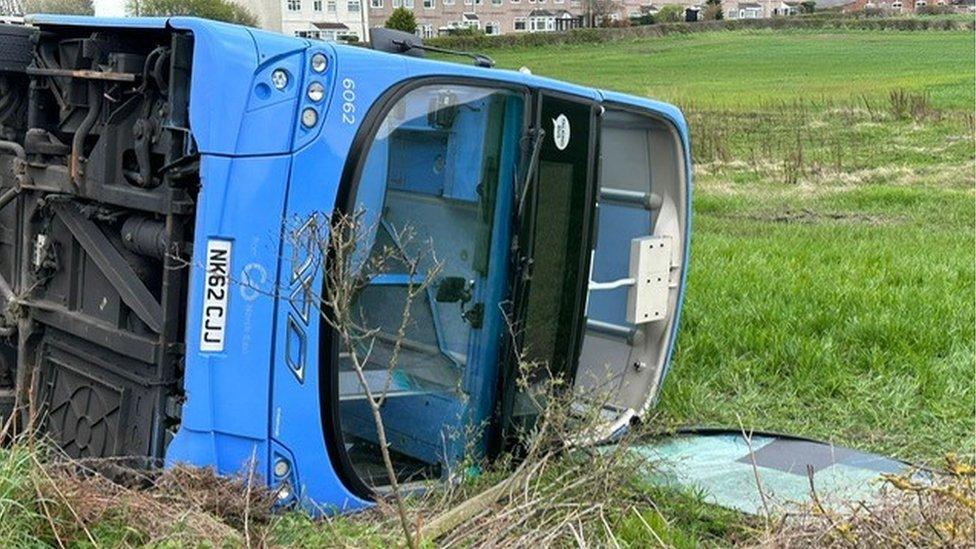 Upstairs window broken on the overturned bus