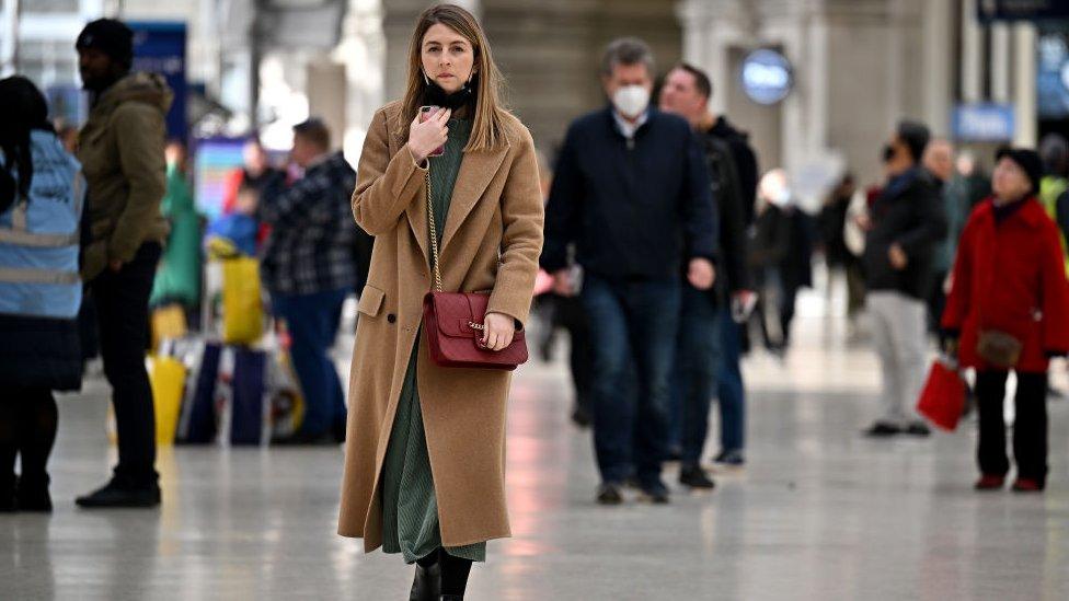 A woman takes down her mask at Waterloo station