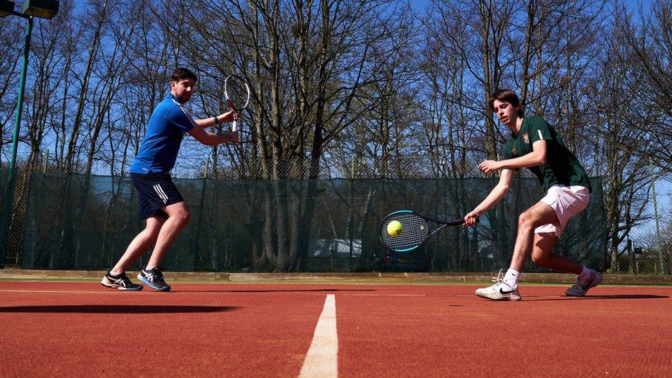 Two people playing tennis outdoors