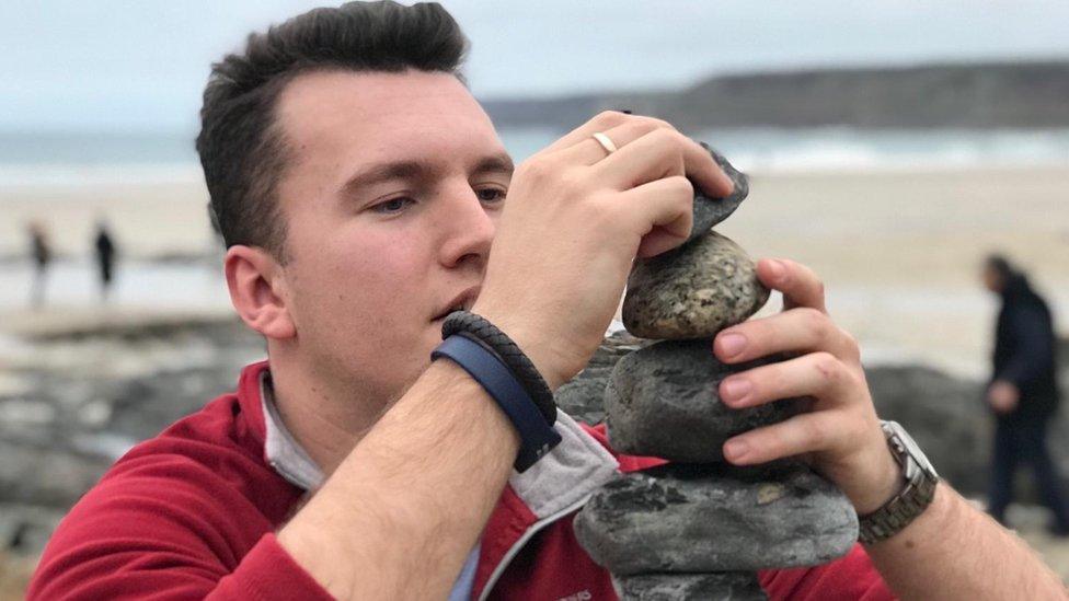 James Rourke piling up stones on a beach