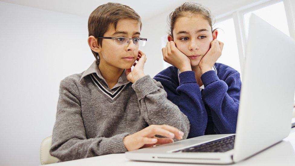 Boy and girl look at a laptop together