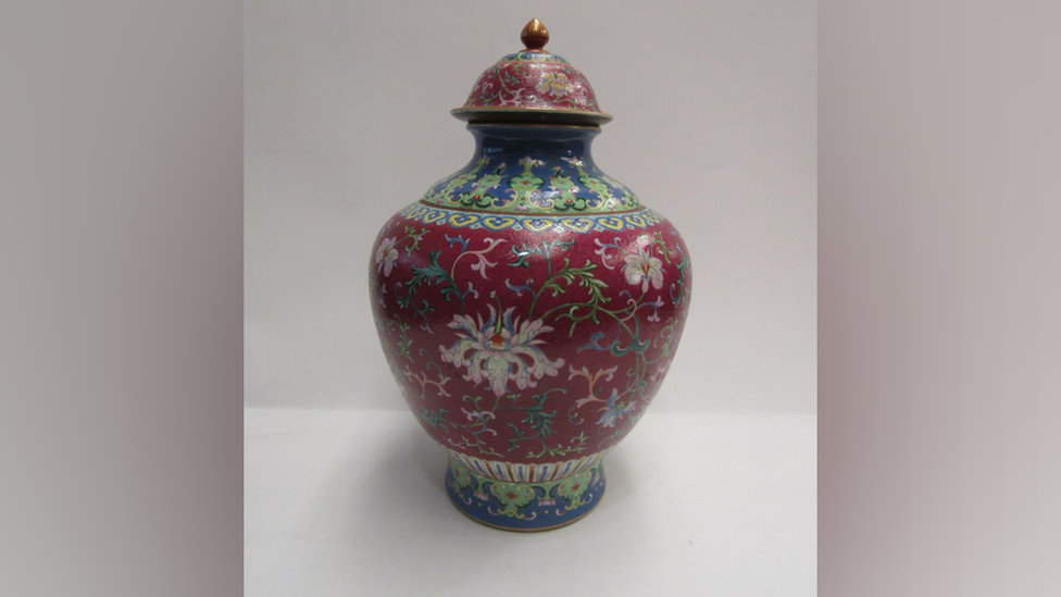 An ornate Chinese vase from the 18th century. It has a aubergine coloured background with foliage design.