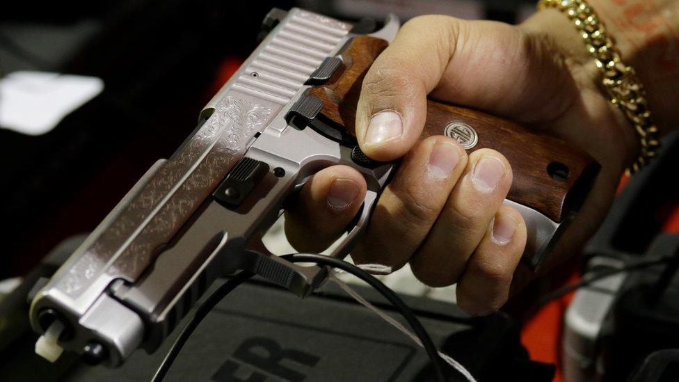 A customer looks at a SIG Sauer hand gun at a gun show held by Florida Gun Shows, Saturday, Jan. 9, 2016, in Miami