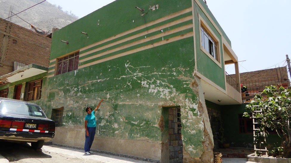 Resident showing the height reached by the mud and rocks after the mudslide in March