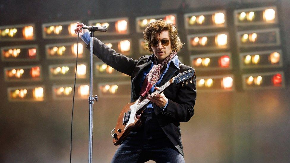 Alex Turner of the Arctic Monkeys on stage playing a guitar at Ashton Gate