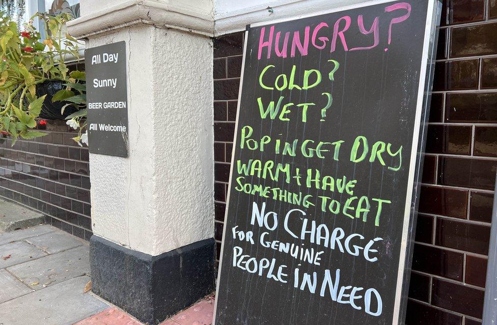 Six Bells sign which reads: "Hungry? Cold? Wet? Pop in, get dry, warm and have something to eat. No charge for genuine people in need."