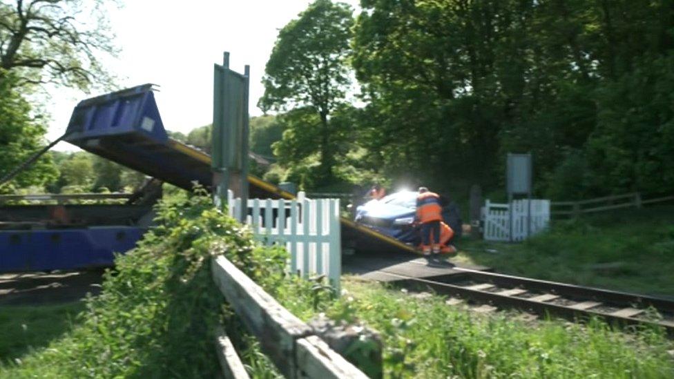 Image of car being put on back of truck at level crossing