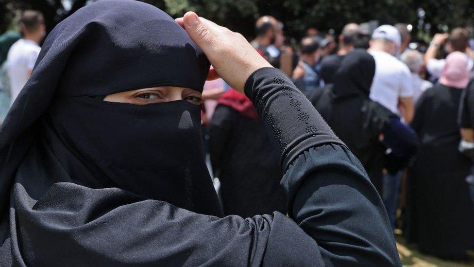 A woman adjusts her headscarf during a protest against Israel's Citizenship and Entry law outside the Israeli parliament in Jerusalem on 5 July 2021