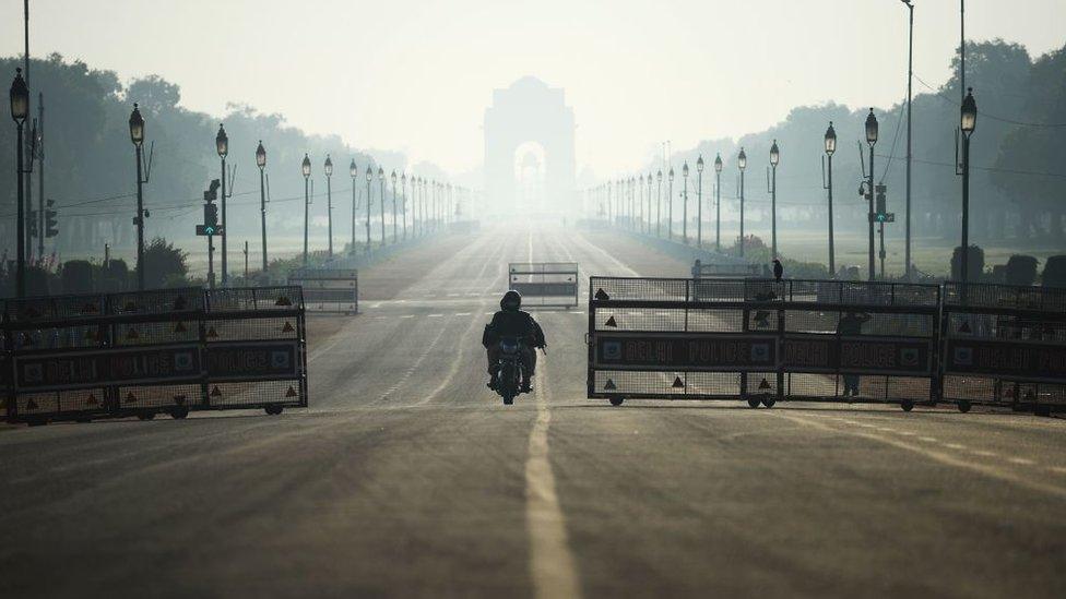 A motorist rides through deserted Rajpath road during a one-day Janata (civil) curfew imposed as a preventive measure against the COVID-19 coronavirus, in New Delhi on March 22, 2020.