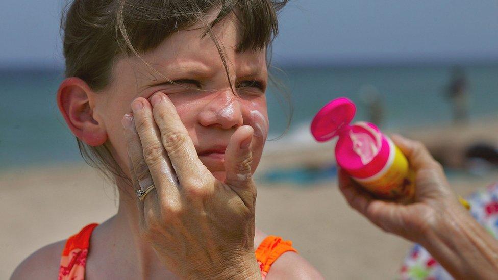 Child having sunscreen put on face