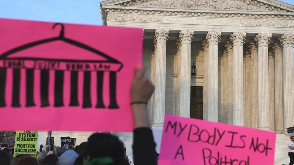 the US supreme court building with a protest placard in front reading 'my body is not a political playground'