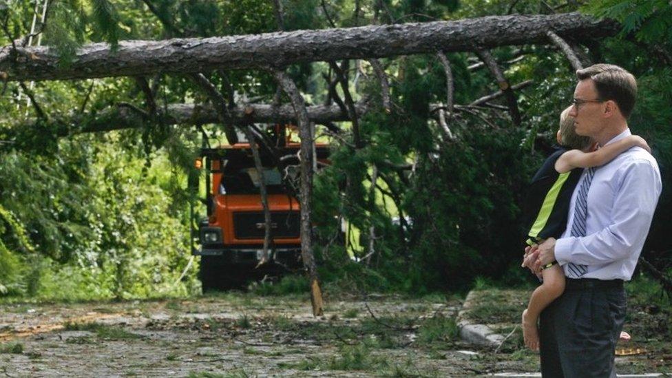 Robert Long and his son watch workers removing downed trees during clean-up operations in the aftermath of Hurricane Hermine in Tallahassee, Florida