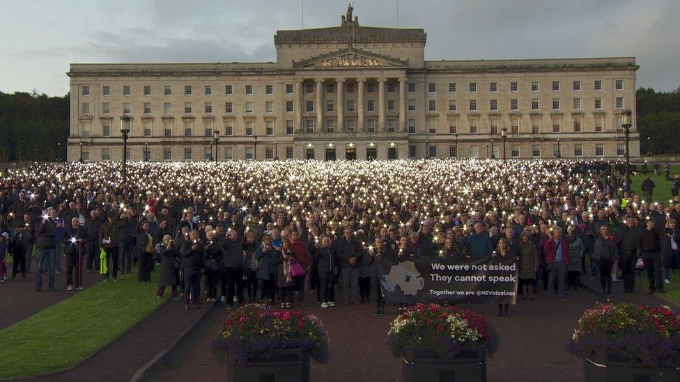 Protesters stand in front of Stormont shining torches