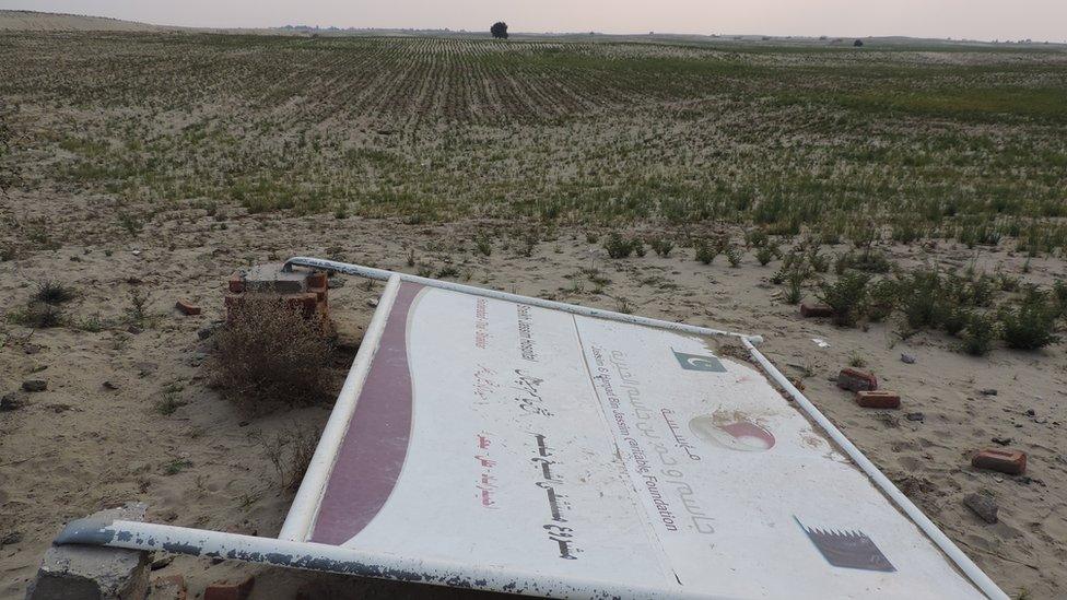 A collapsed signboard of the Jassim & Hamad bin Jassim Charitable Foundation of Qatar shows a tract of land donated by locals for a hospital near Hyderabad Thal town.