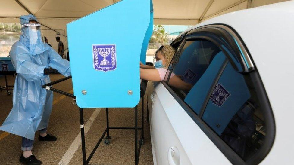 A woman votes from her car at a special mobile polling station for Israelis in quarantine or infected with Covid-19, in Haifa, Israel (23 March 2021)