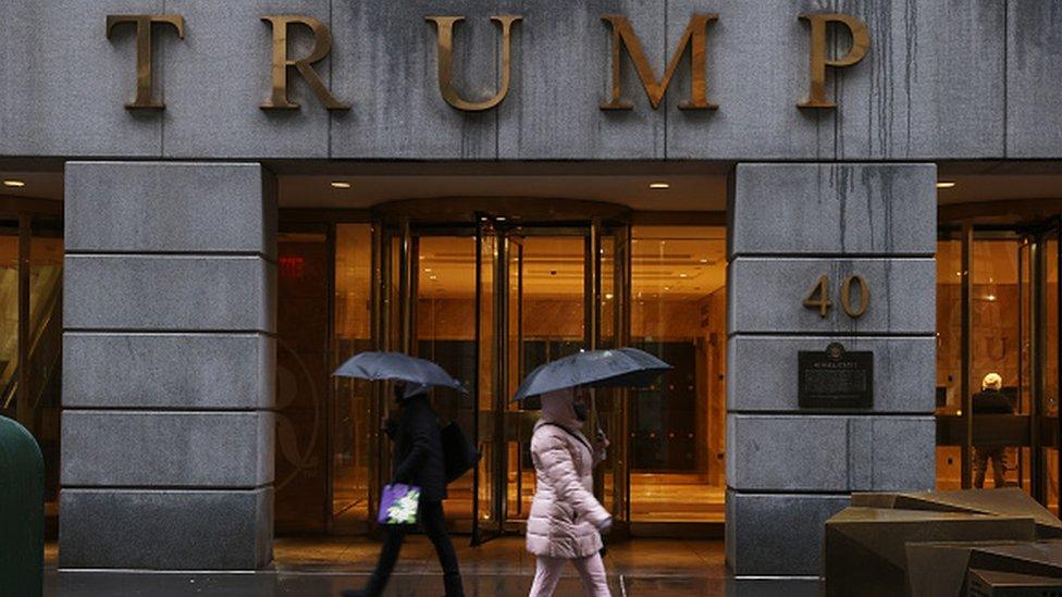 People walk by a Trump-owned property on Wall Street