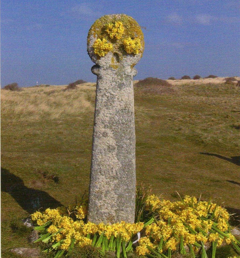 A cross of St Piran covered in daffodils