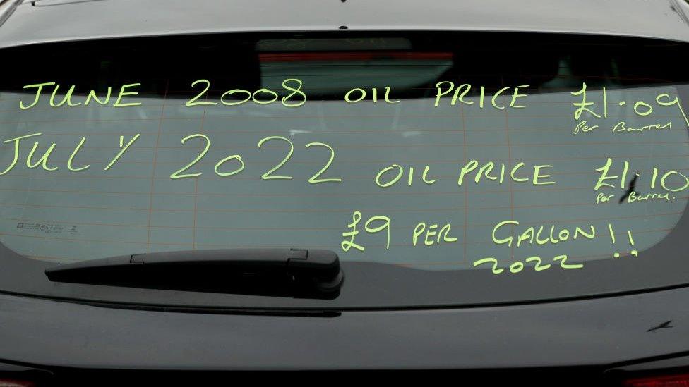 the rear window of a car with writing on the window that says June 2008 oil price £1.09 a barrel - July 2022 oil price £1.10 per barrel - £9 per gallon 2022