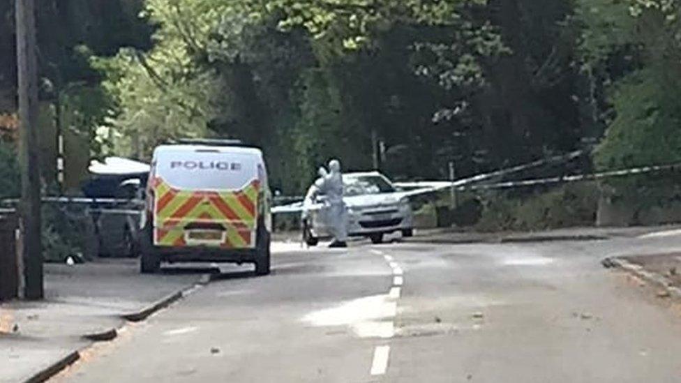 The blue tent with a forensic officer at work behind the cordon