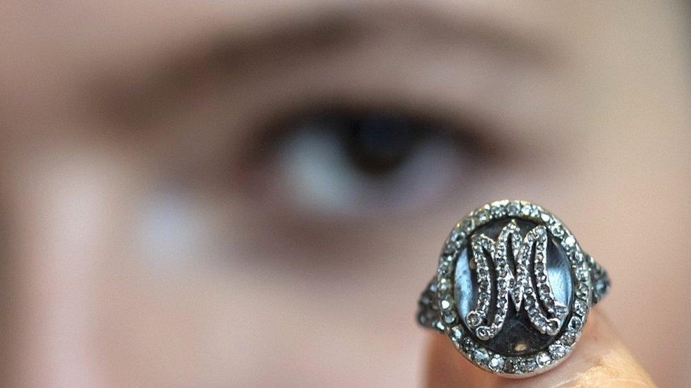 A Sotheby's employee displays a diamond ring bearing the initials MA for Marie Antoinette and containing a lock of her hair during a preview at the Sotheby's in Geneva, Switzerland, on 7 November 2018