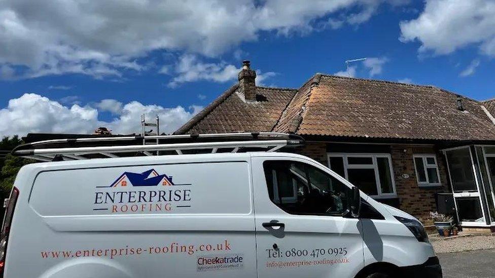 Enterprise roofing van parked outside of a house