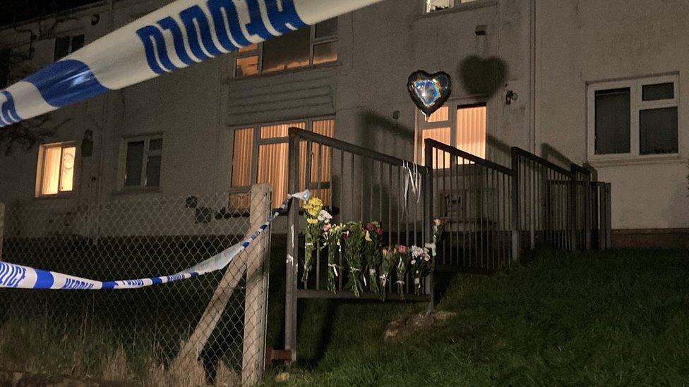 A house with police cordon and floral tributes