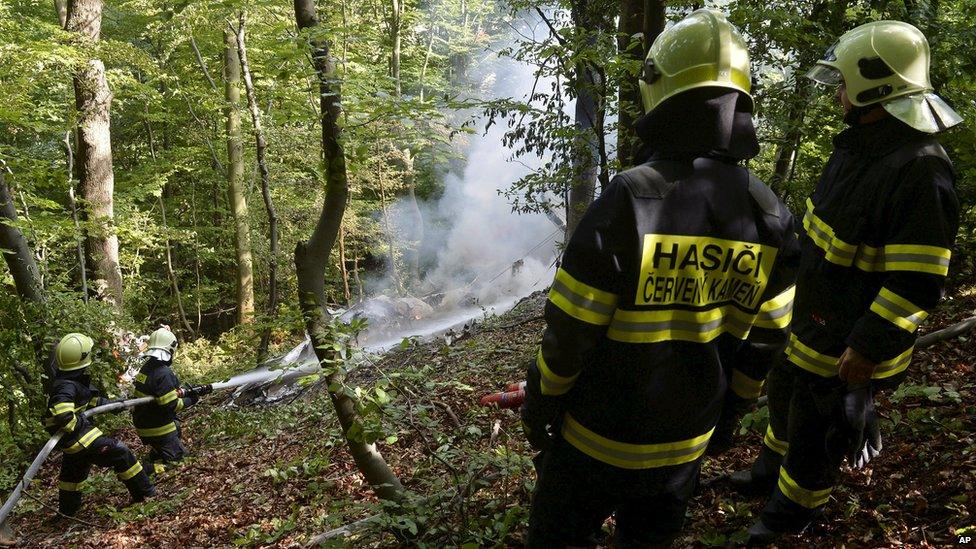 Firefighters work at the crash site of two sport planes near the village of Cerveny Kamen, Slovakia, on 25 August 2015