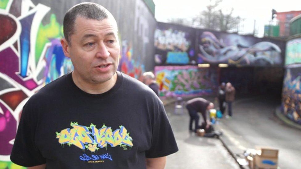 Artist Paul Pilgrim in front of a graffiti wall