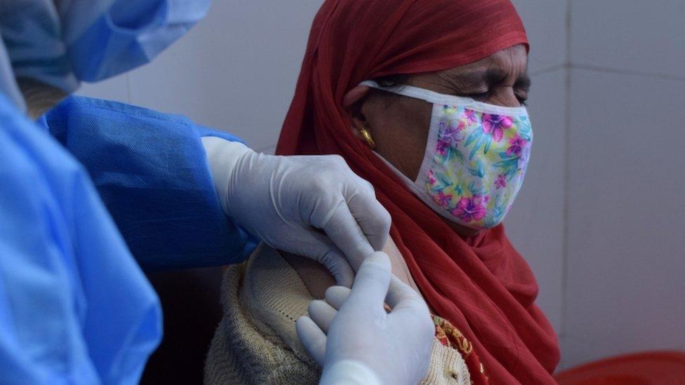 A woman reacts as she receives a dose of COVISHIELD, a coronavirus disease (COVID-19) vaccine manufactured by Serum Institute of India, at a vaccination centre in Srinagar.