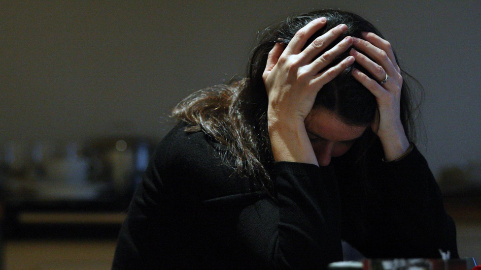 Woman holds head in hands