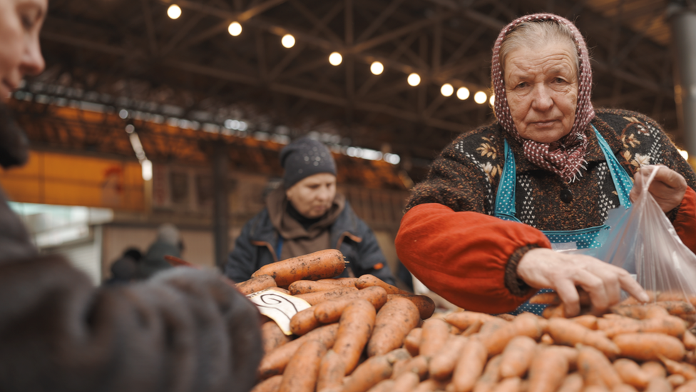 A Moldovan woman puts carrots in a bag