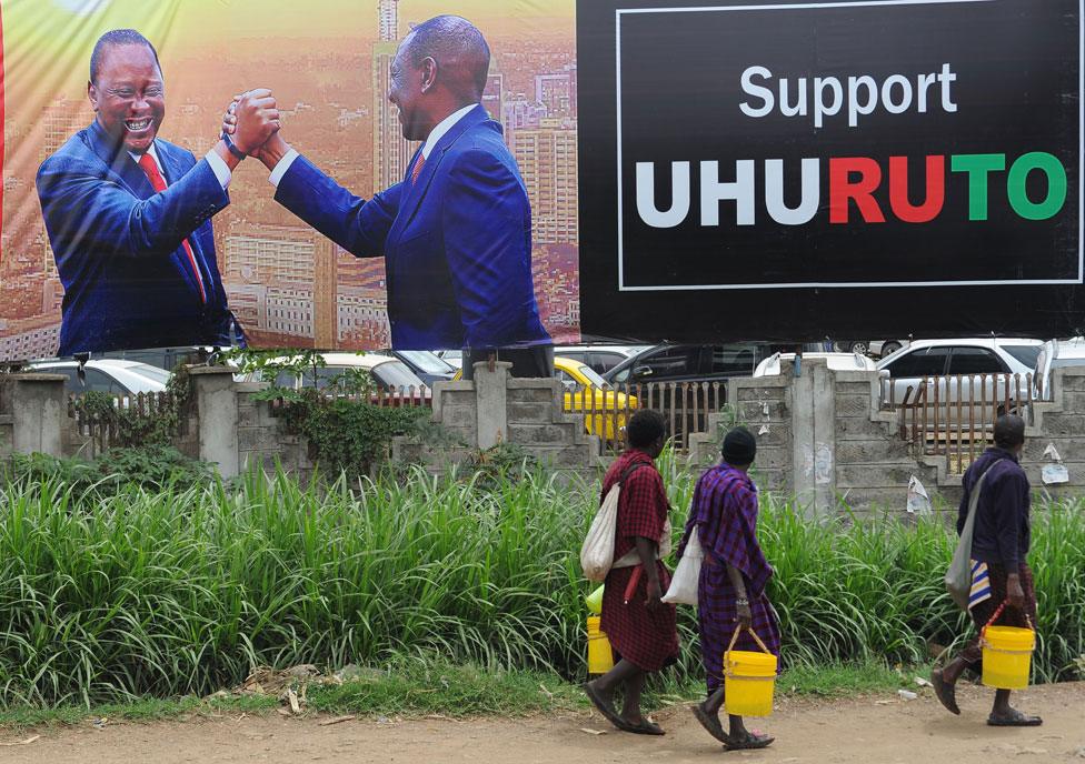 Pedestrians walk past the campaign poster of Kenya's President Uhuru Kenyatta and Deputy-President William Ruto in Nairobi on October 23, 2017, ahead of the repeat elections. Kenyans head to the polls on October 26 for a second time this year after the Supreme Court overturned the August election victory of President Uhuru Kenyatta.