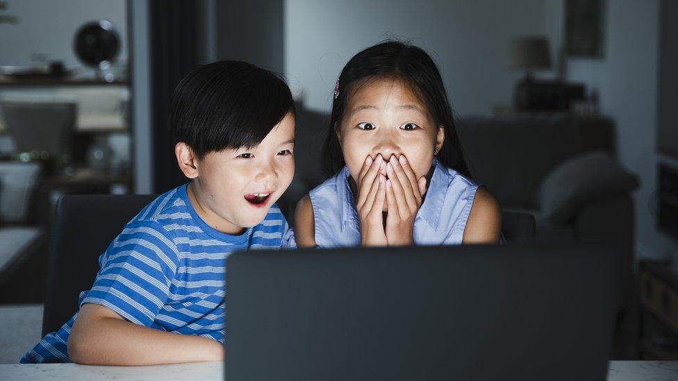 Two kids looking shocked at a laptop