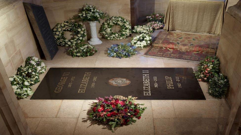 The stone reads "George VI 1895-1952" and "Elizabeth 1900-2002" followed by a metal Garter Star, and then "Elizabeth II 1926-2022" and "Philip 1921-2021".