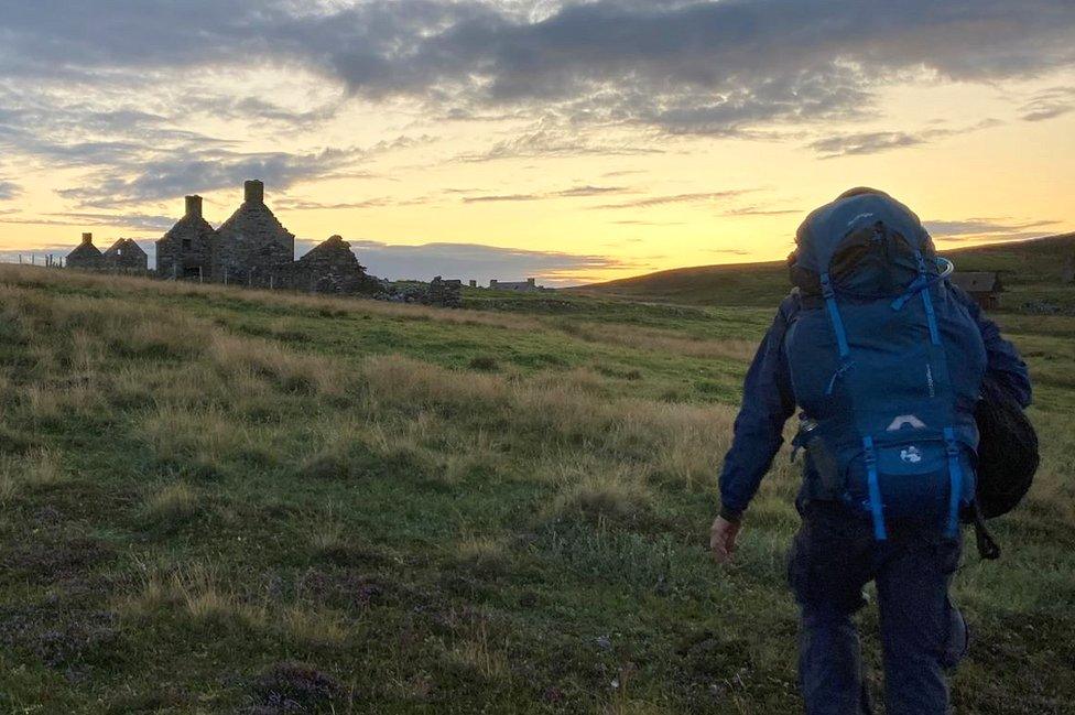 Rob walks up to one of the ruined houses