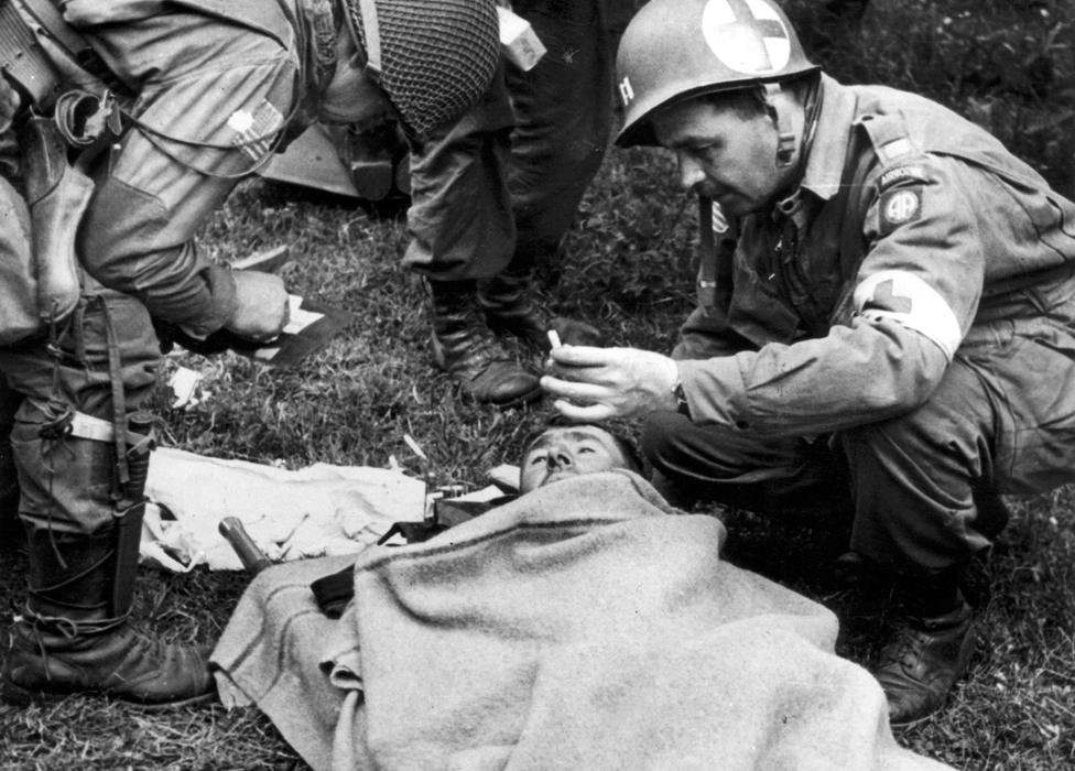 A doctor of the US 82nd Airborne division cares for a wounded German prisoner in Normandy