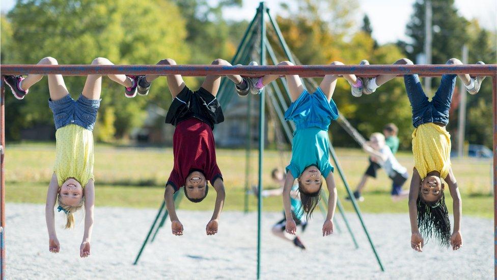 four children hanging from climbing frame