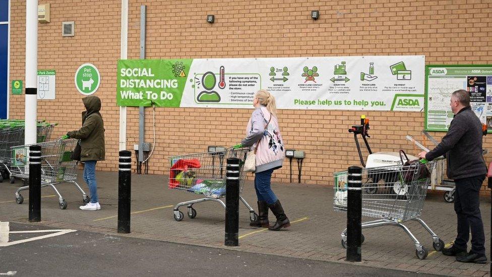 Shoppers queue using social distancing outside supermarket in England