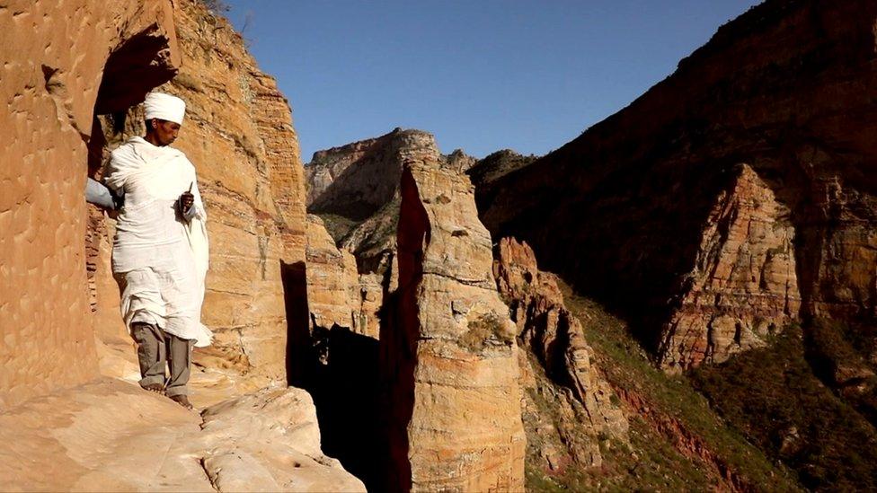 Priest stands next to a cliff edge