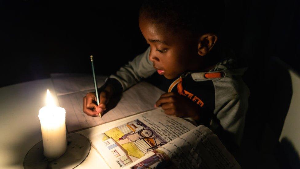 A child doing his homework by candlelight in Harare, Zimbabwe - June 2019