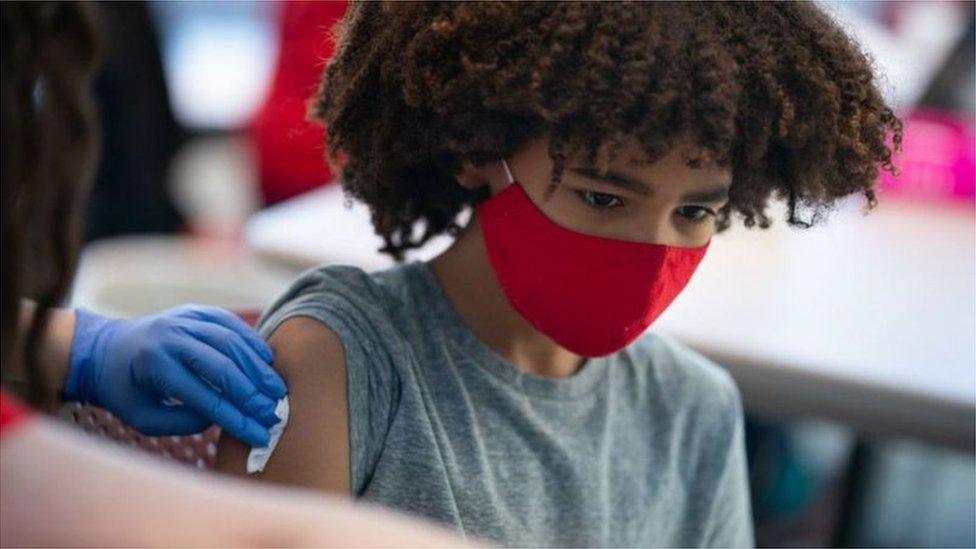 Young boy getting a vaccine while wearing a face mask