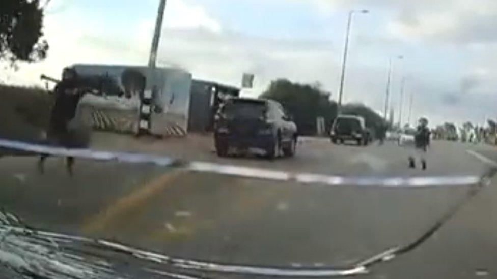 A still image from a dashcam video showing an armed militant next to a bus stop holding what appears to be an RPG