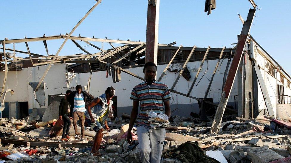 Migrants carry the remains of their belongings from among rubble at a detention centre for mainly African migrants that was hit by an airstrike in the Tajoura suburb of the Libyan capital of Tripoli, Libya July 3