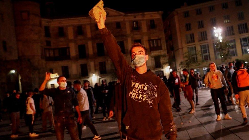 A demonstrator in Barcelona holds a rock aloft