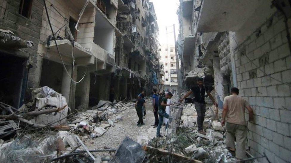 Syrian citizens inspect damaged buildings after airstrikes hit Aleppo (29 July 2016)